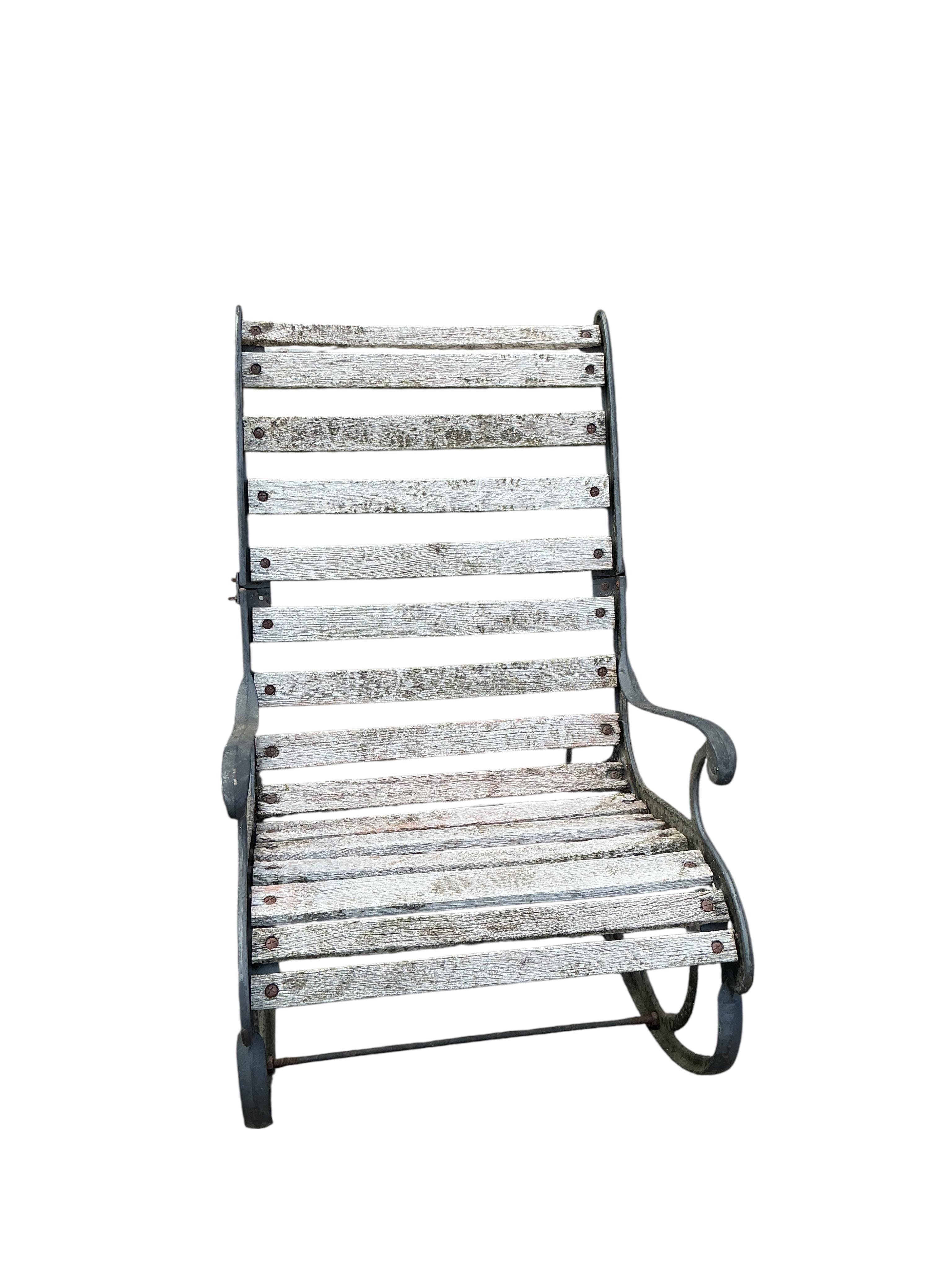A pair of slatted cast metal garden rocking chairs
